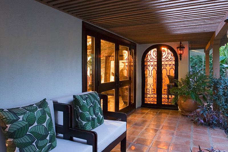 An opulent house's patio is adorned with outdoor furniture and a beautiful front door.