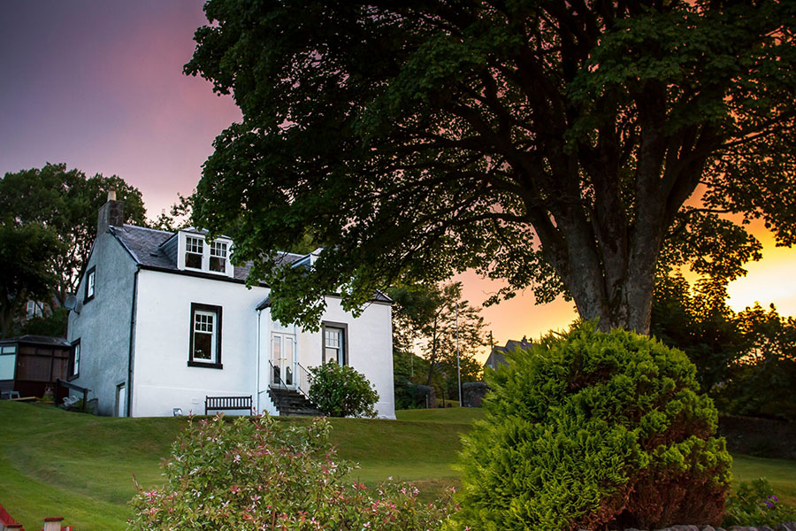 A picturesque white house is set against a setting sun.